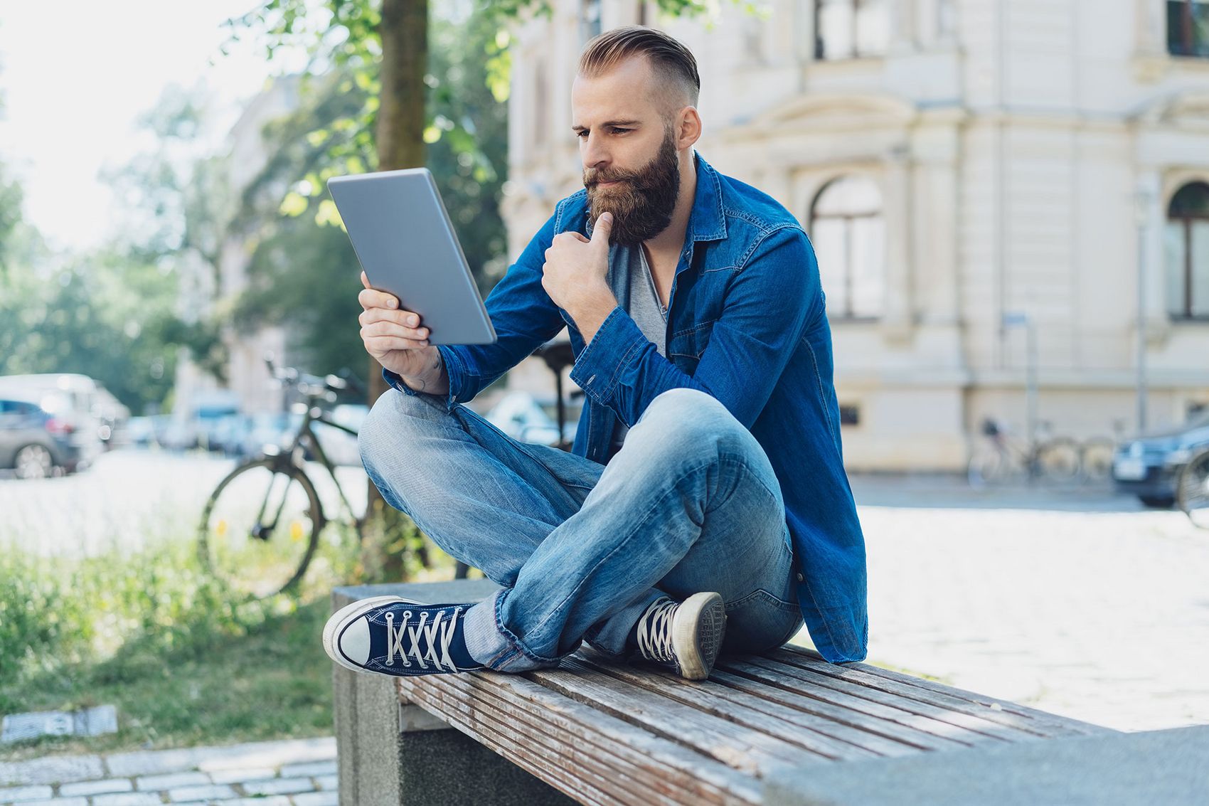 Mann mit Tablet auf einer Bank